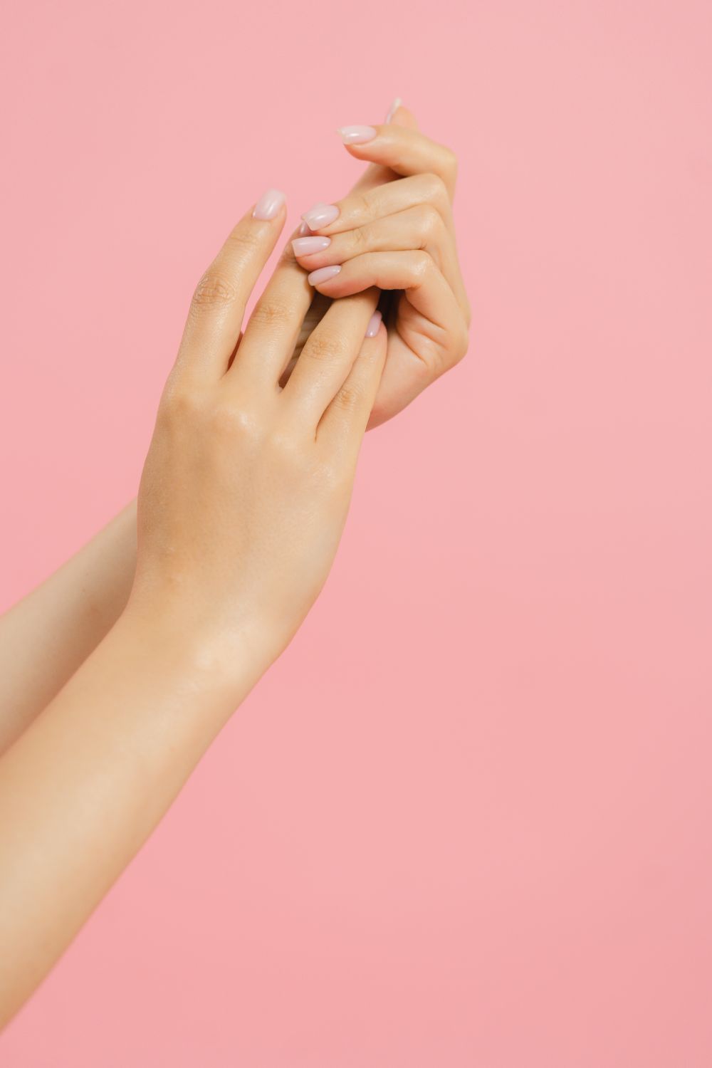 Freshly manicured hands against a soft pink background